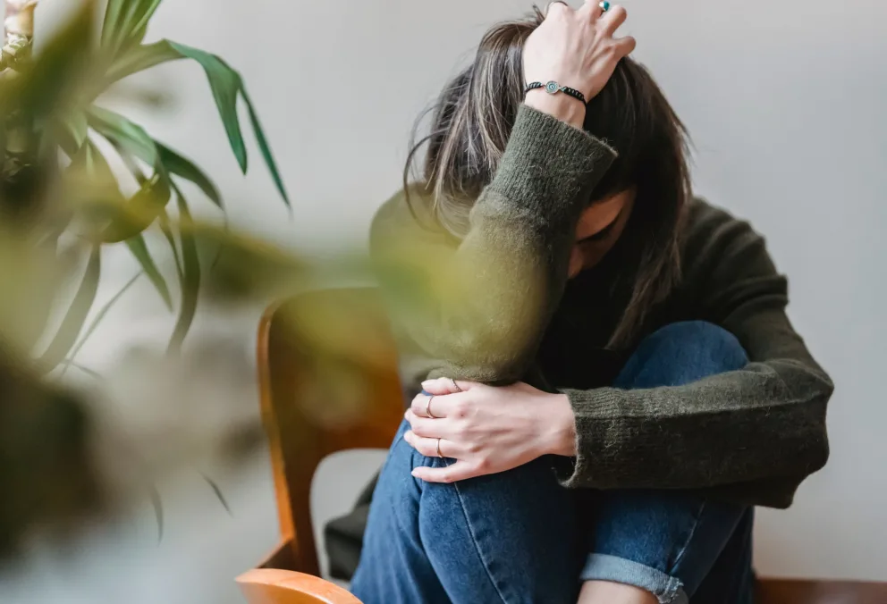 Girl sitting on ground with arm covering face